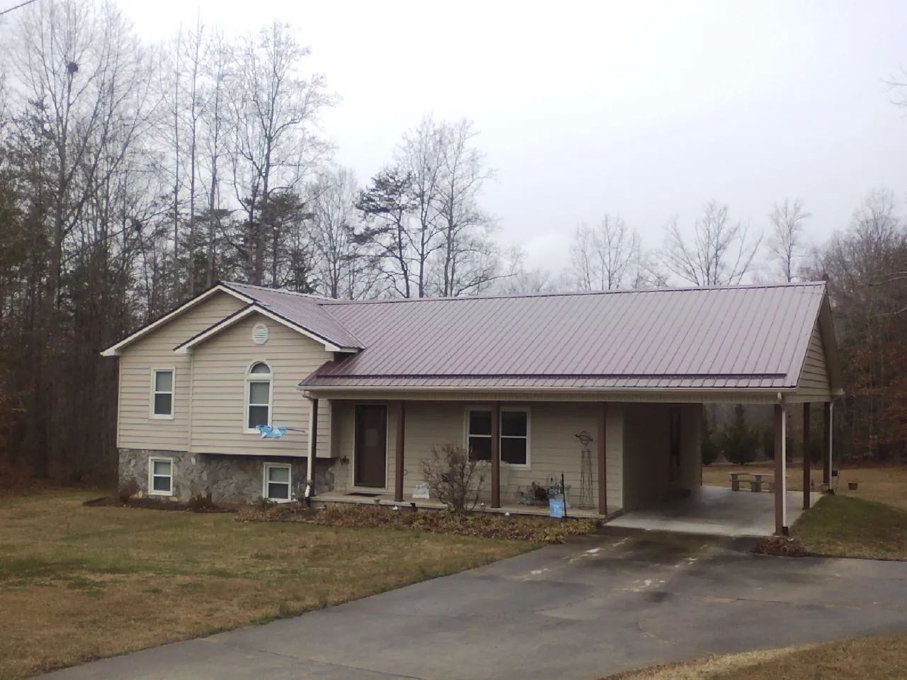 Burgundy metal roof on a tan split level home with an attached carport in Kimberly