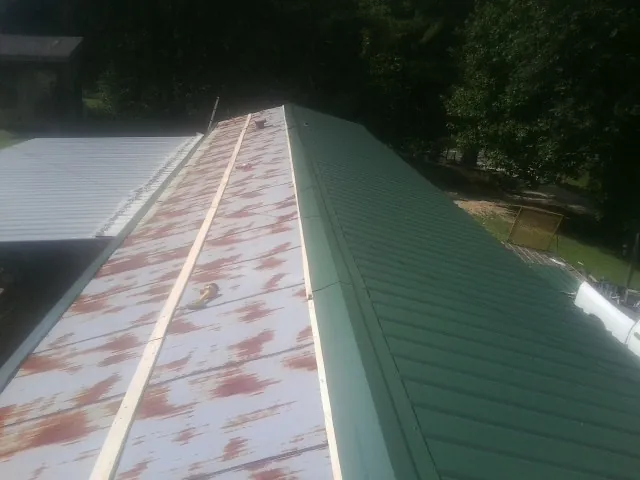 Old rusted panels beside newly installed green metal roofing — Wind Damage Roof Repair by Roofing Brothers in Kimberly